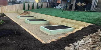 Newly constructed raised garden beds in a Charlotte backyard showcase the skillful work of local landscapers, with fresh soil and meticulous borders.