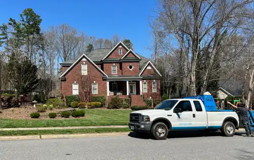 Brick house with a well-maintained lawn and a Barker Brothers LLC truck parked in front in Charlotte.
