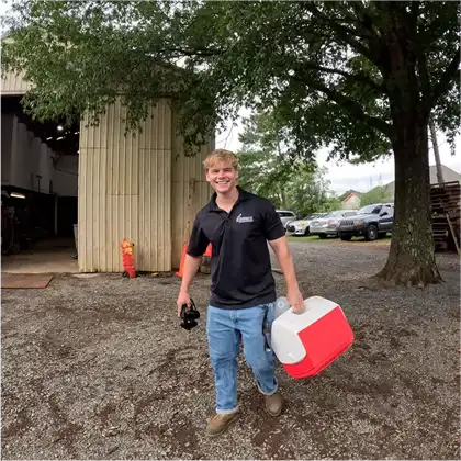 Happy lawn care worker carrying equipment after a successful mowing session in Charlotte, NC.